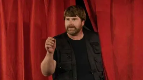 Mann, der vor rotem Vorhang steht